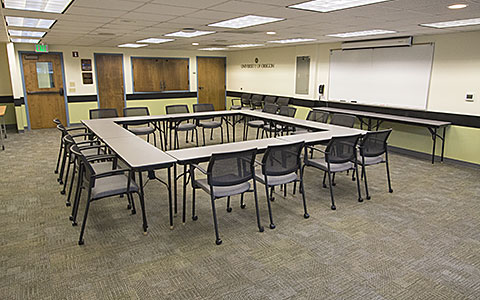 Small classroom with tables and chairs positioned in a square for Eugene Event Facilities page.